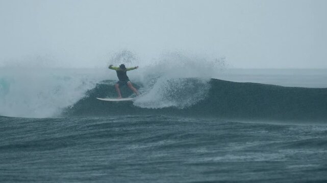 Surfer rides the wave in the ocean during rainy day