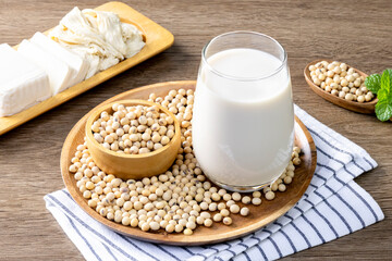 Soy milk in a glass and soybeans on the wooden table.