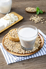 Soy milk in a glass and soybeans on the wooden table.