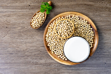 Soy milk in a glass and soybeans on the wooden table.