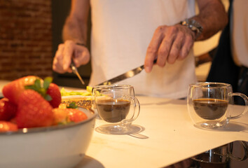 Man preparing fresh strawberries and coffee for a healthy morning breakfast