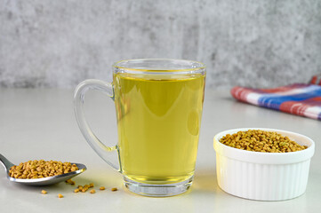 Fenugreek tea served in a glass cup.