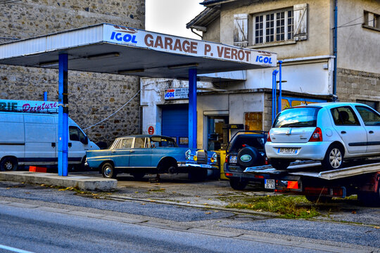 Aurec-sur-Loire, France - October 12th 2024: Retro-style view of a blue Mercedes-Benz W111 (220&ndash;300) under repair on a garage parking lot, raised on a jack with one wheel missing.