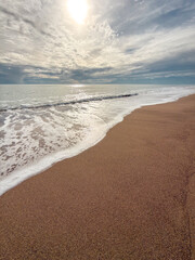 Gentle sea waves touching sandy beach under dramatic cloudy sky