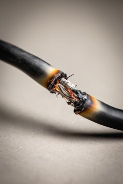 Close-up of a burnt electrical cable with exposed copper and melted insulation