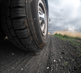 A tire is shown in the dirt with a cloudy sky in the background