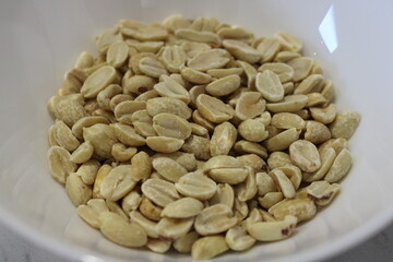 Peanut kernels in a white bowl ready for cooking or snacking on the kitchen countertop