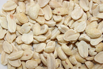 Shelled peanuts are placed in a pile on a flat surface in a close-up view during daylight