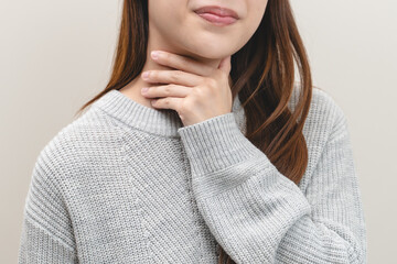 Sore throat in flu season. Young asian woman touching her neck and feeling pain in throat in the bedroom at home.