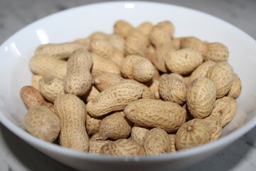 Bowl filled with unshelled peanuts on a table, perfect for snacking or cooking at home