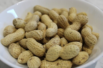 Bowl filled with raw peanuts on a table in a kitchen setting for casual snacks or cooking