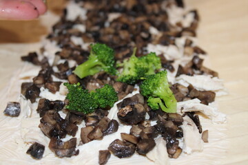 Cooking a dish with mushrooms, chicken, and broccoli on a wooden surface in a kitchen setting
