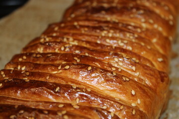 Freshly baked bread with sesame seeds on a baking sheet arranged in straight lines