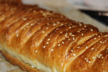 Freshly baked pastry with sesame seeds on top placed on a baking sheet in a kitchen setting