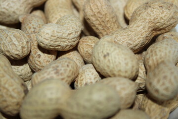 Peanuts scattered on a surface showing their rough shells in a close view captured in a natural light setting