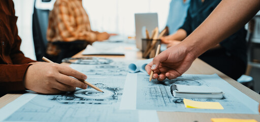 A dynamic group of creative professionals engages in collaborative design efforts at a modern office, with sketches, notes, and tools spread across the table. SACTR