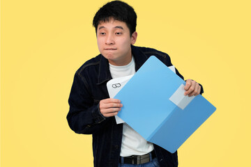 Worried young Asian student or professional looking disappointed at a document showing a B grade inside a blue folder, symbolizing failure, low performance, or academic struggle in yellow background