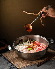 Delicious Hot Pot with Assorted Ingredients and Sauce Being Poured.