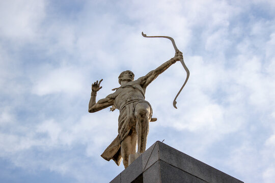 Bronze archer statue standing tall against a cloudy blue sky background around the Gelora Bung Karno Sports Complex.