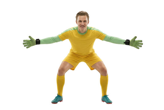Focused male soccer goalkeeper in yellow uniform and green gloves ready to block a shot on white background.