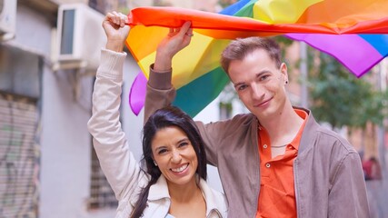 Diverse couple holding rainbow flag celebrating inclusion and pride