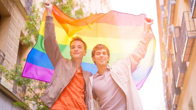 Gay couple celebrating inclusion holding rainbow flag