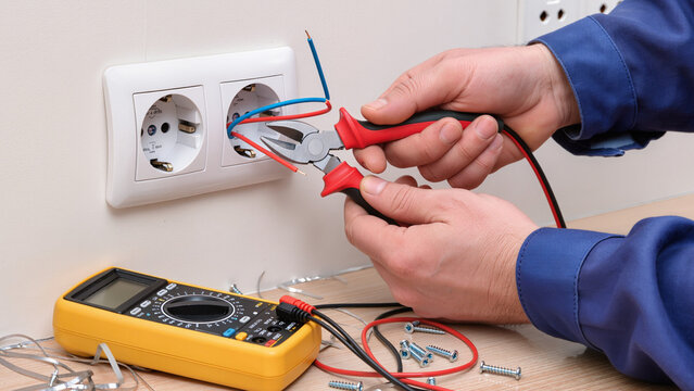 electrician repairing electrical outlet - Powered by Adobe