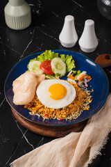 Delicious Nasi Goreng with Fried Egg and Crackers on a Blue Plate.