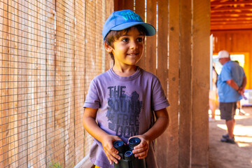 Curious child exploring with binoculars at the british columbia wildlife park in kamloops, canada