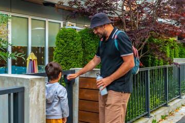 Father opening gate for son at daycare in vancouver