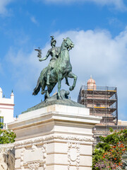 Obraz premium Cadiz, Spain - April 16, 2025: monument in homage to the Constitution of 1812 in Cadiz, with tourists swimming in the sea during the Easter holidays in Cadiz, Spain.