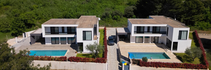 Aerial view of two stunning modern luxury villas with private swimming pools, elegant architecture,...