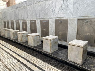 A row of modern ablution (wudu) stations in a mosque, featuring sleek marble seating and walls. This clean, geometric design provides a dedicated space for ritual purification before prayer.