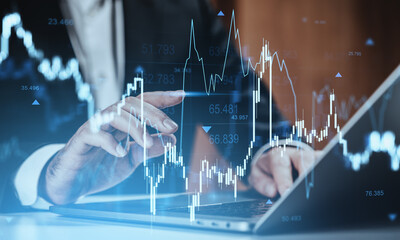 Businessman analyzing stock market chart on digital screen while using laptop in futuristic finance concept background with glowing data graphics.
