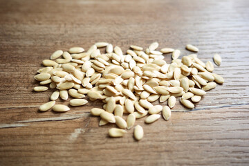 Seeds scattered on a wooden surface in a kitchen with natural light coming through a nearby window