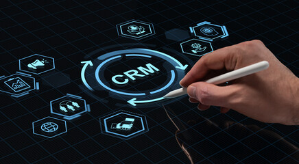 Hand using stylus to interact with digital CRM interface on futuristic touchscreen with tech icons and holographic elements on dark grid background.