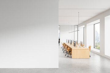 Modern office interior with large white empty wall for poster mockup and shared workstation area...