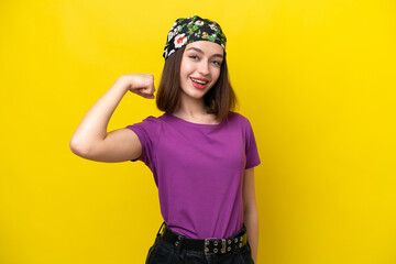 Young Ukrainian woman isolated on yellow background doing strong gesture