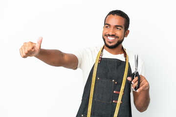 Young Ecuadorian design man holding scissors isolated on white background giving a thumbs up gesture