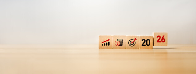 Wooden blocks displaying business growth icons, financial savings symbols, a target goal, the year...