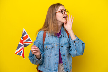 Teenager Russian girl holding an United Kingdom flag isolated on yellow background shouting with...