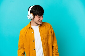Young Russian man isolated on blue background listening music