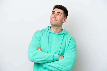 Young caucasian man isolated on white background looking up while smiling