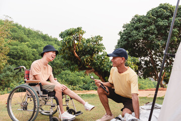 A wheelchair user laughs with a family while camping outdoors. They share a joyful moment during tent setup, showing friendship, inclusion, accessibility, and a positive lifestyle surrounded by nature