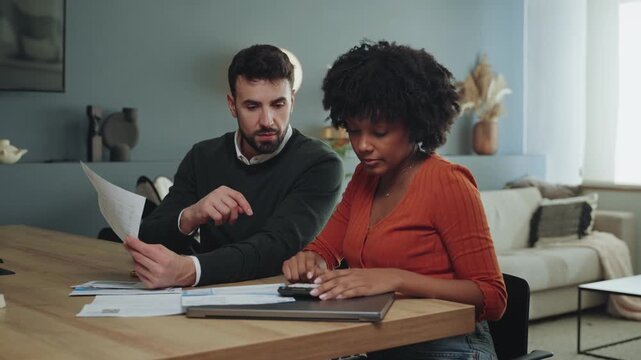 Young mixed couple family do paper work paying household utility bills planning finances and domestic economy at home