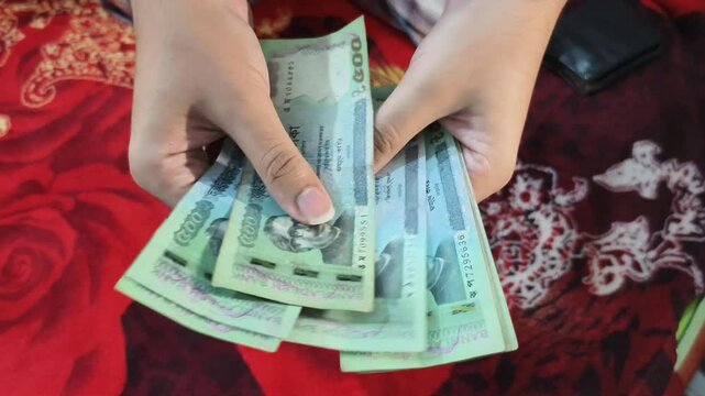 closeup of male hands counting bangladeshi five hundred taka banknotes on red floral background