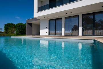 Modern luxury villa with swimming pool and clean minimalist architecture under a blue sky....