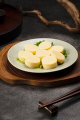 Steamed Egg Tofu Slices on a White Plate with Green Garnish.