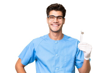 Young dentist man holding tools over isolated background posing with arms at hip and smiling