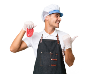 Butcher caucasian man wearing an apron and serving fresh cut meat over isolated background pointing to the side to present a product
